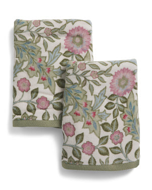 Two folded cotton towels with a vintage floral pattern featuring pink flowers, green leaves, and muted sage green borders, displayed on a clean white background.